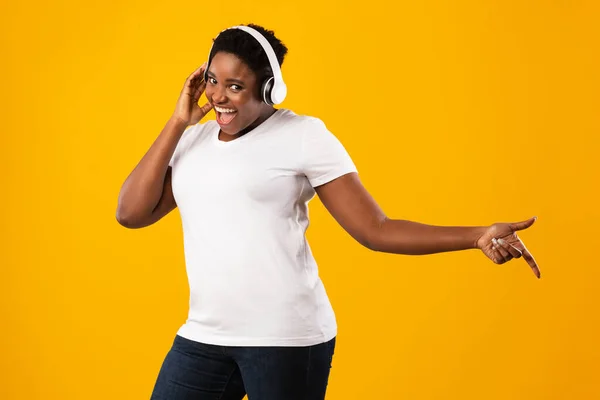 Overweight Black Lady ouvir música em fones de ouvido sobre fundo amarelo — Fotografia de Stock