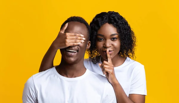 Beautiful black woman covering man eyes, showing silence gesture — Stock Photo, Image