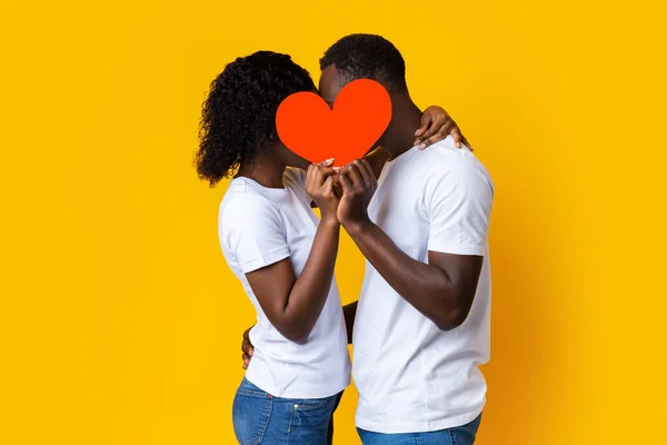 Afroamericano coppia baci e nascondersi dietro rosso cuore — Foto Stock