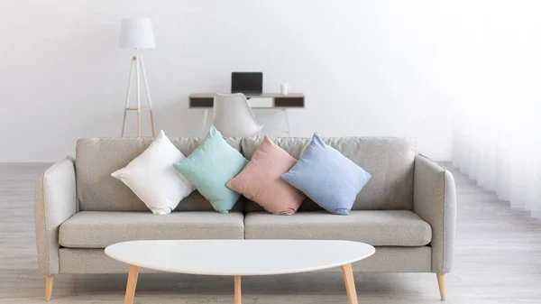 Mesa blanca con sofá y almohadas de colores en el salón — Foto de Stock