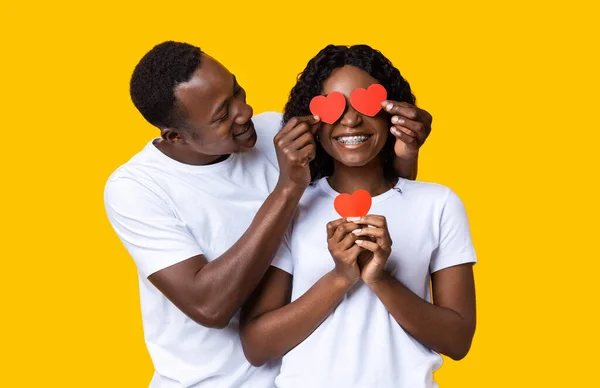 Loving zwart guy bedekken zijn vriendin ogen met valentijnskaarten — Stockfoto