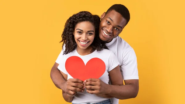 Amare nero coppia tenendo cuore abbracciare posa su sfondo giallo — Foto Stock