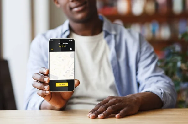 Fekete férfi gazdaság okostelefon megnyitott taxi szolgáltatások mobil alkalmazás a képernyőn — Stock Fotó
