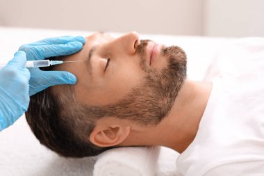 Güzellik uzmanı orta yaşlı bir adam için yüz gerdirme prosedürü uyguluyor.