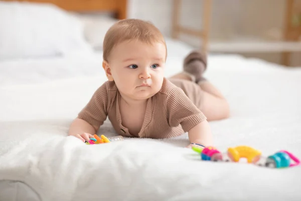 Söt liten bebis leker med leksaker på sängen — Stockfoto