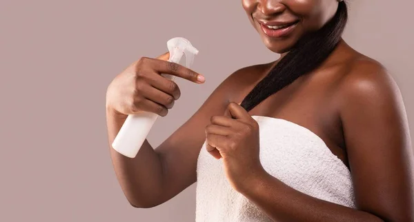 Termina dividida. Jovem senhora negra aplicando tratamento de reparação de cabelo spray após banho — Fotografia de Stock