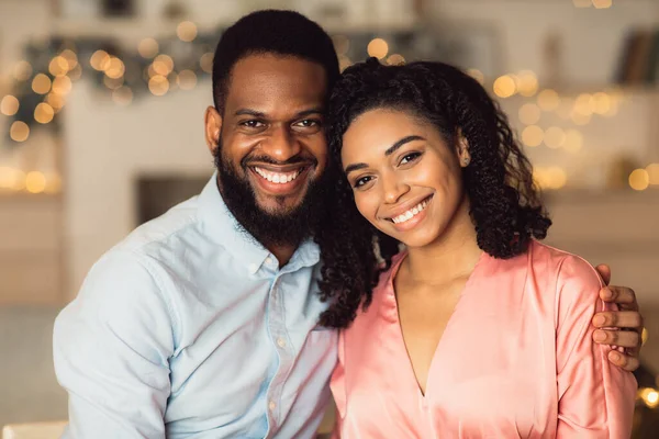 Lächelnder schwarzer Mann umarmt seine Frau, blickt in die Kamera — Stockfoto