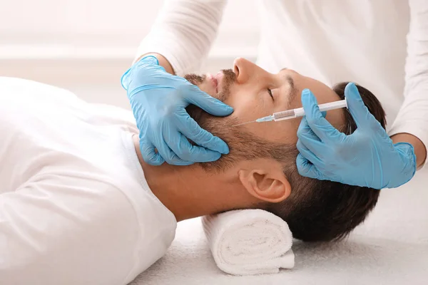 Kosmetolog provádějící na klinice anti-aging proceduru pro muže středního věku — Stock fotografie