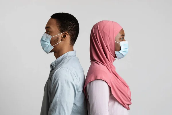 Moslim zwart paar in het gezicht maskers staan rug aan rug — Stockfoto