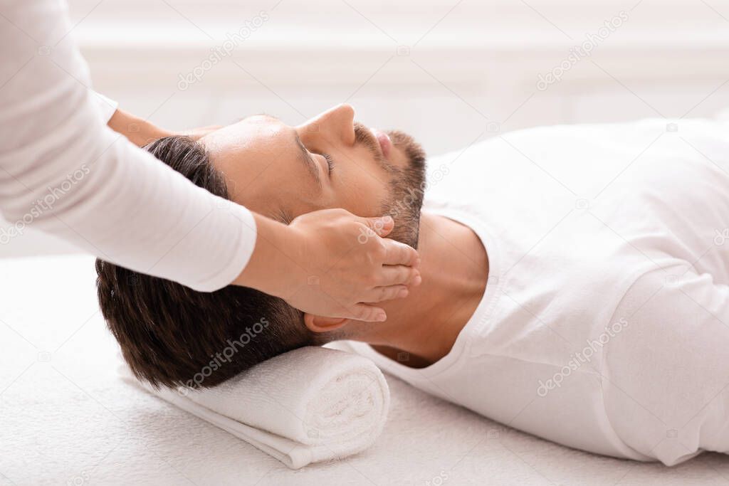 Caucasian businessman attending spa salon, getting face massage, side view