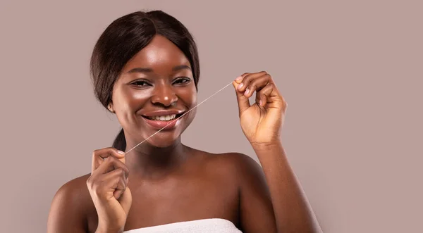 Oral hygien. Attraktiv afrikansk kvinna som använder tandtråd och ler mot kameran — Stockfoto