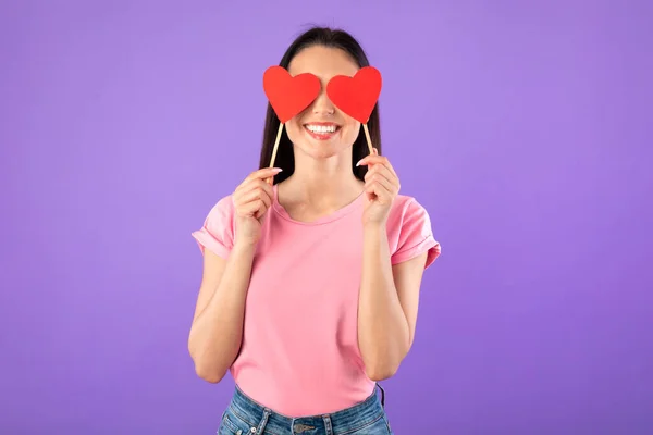 Mulher sorridente segurando dois corações, cobrindo os olhos — Fotografia de Stock