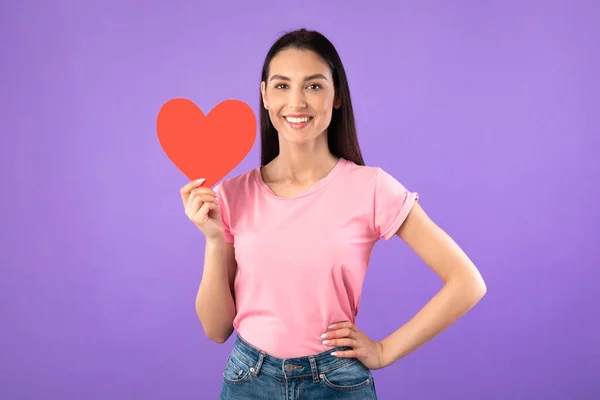 Smiling woman holding heart, posing and looking at camera — Stock Photo, Image