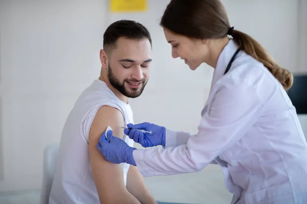 Fiatal férfi beteg vakcinázása, kovid-19 vakcina injekció beadása a klinikán — Stock Fotó