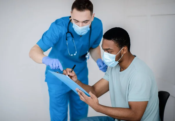 Jeune homme noir signant le consentement officiel avant l'injection de vaccin covid-19 au centre de santé — Photo