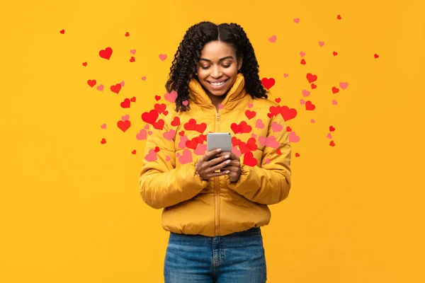 Boldog afrikai nő használ telefon küldése, mint az ikonok, sárga háttér — Stock Fotó