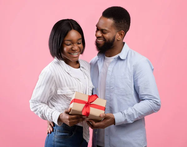 Jeune couple marié célébrant la Saint-Valentin, tenant boîte cadeau enveloppé sur fond de studio rose — Photo