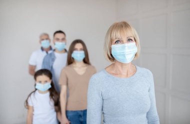 Hastanede Coronavirus 'a karşı aşı için sırada bekleyen maskeli yaşlı kadın.