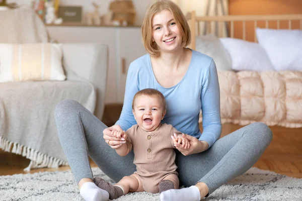 Mère heureuse jouant avec son bébé riant, assise sur le sol — Photo