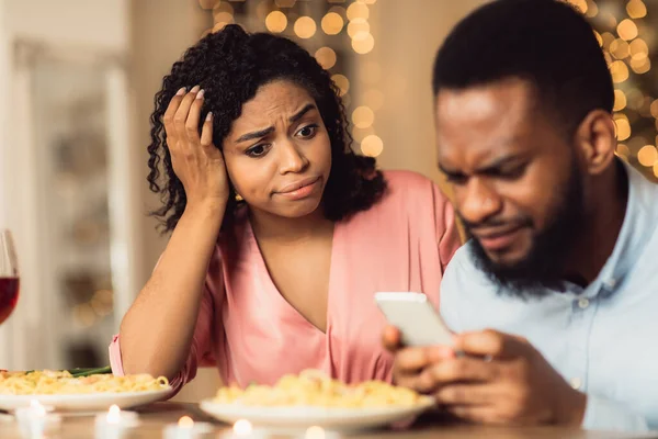 Δυστυχισμένη μαύρη γυναίκα βαριέται σε ημερομηνία, ο άνθρωπος που χρησιμοποιεί το τηλέφωνο — Φωτογραφία Αρχείου