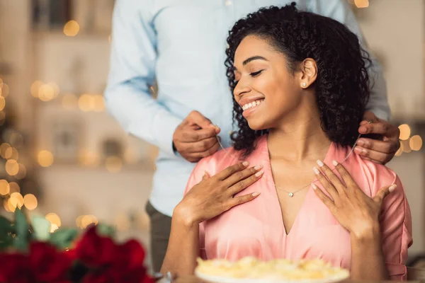 Молодой черный парень носит ожерелье на своей счастливой женщине — стоковое фото