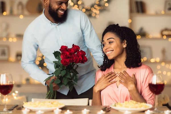 Junger schwarzer Mann schenkt Frau rote Rosen — Stockfoto