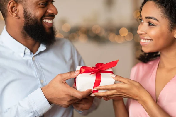 Junger schwarzer Mann schenkt seiner glücklichen Frau eine Geschenkbox — Stockfoto