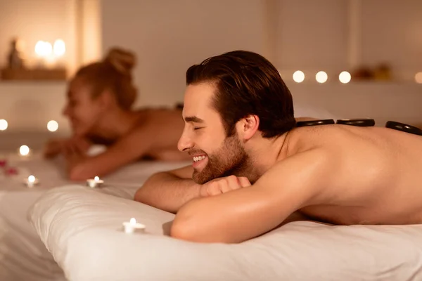 Echtgenoot en vrouw ontspannen ontvangst warm stenen massage in spa Nederlands — Stockfoto