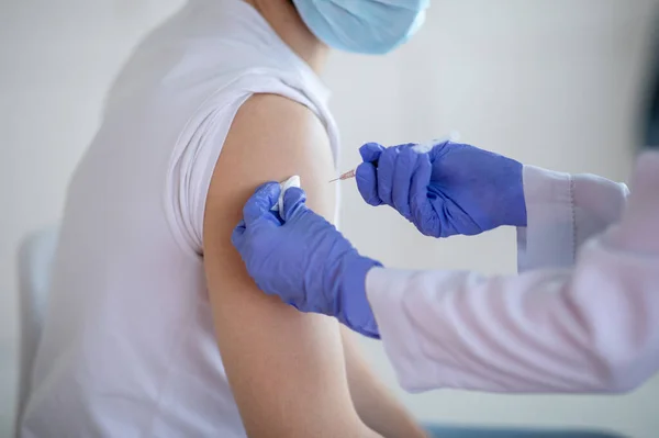 Ausgeschnittene Ansicht eines jungen männlichen Patienten, der in der Klinik Coronavirus-Impfstoff injiziert bekommt, Nahaufnahme — Stockfoto