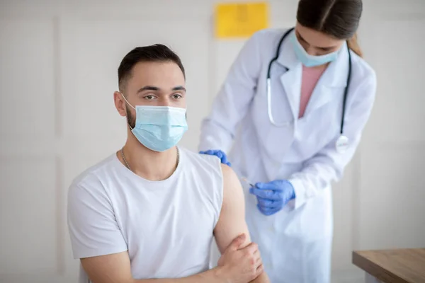 Immunizálás és fertőző betegségek koncepciója. Koronavírus vakcinát injekciózó orvos férfi betegnek a kórházban — Stock Fotó