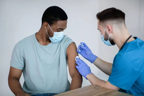 Paciente varón afroamericano vacunado contra covid-19, que recibe la vacuna antiviral inyectable en el centro de salud —  Fotos de Stock