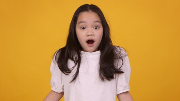 Studio portrait de petite fille asiatique sentiment d'étonnement, couvrant son ouvert dans la bouche de choc avec les mains — Video