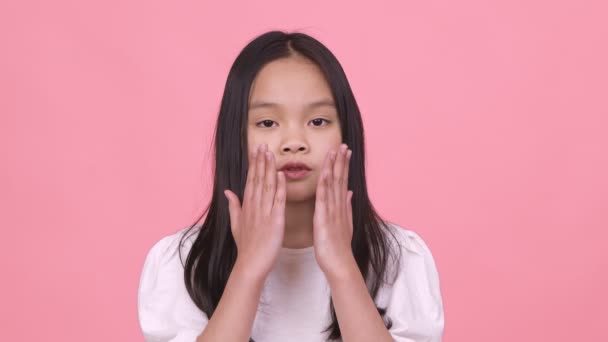 Söt liten asiatisk flicka skicka slag kyss till kameran, uppriktig kärlek känslor, rosa bakgrund, slow motion — Stockvideo