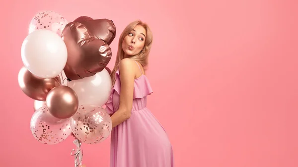 Belle femme blonde en robe mignonne tenant des ballons, portant ses lèvres pour baiser, étant ludique sur fond rose — Photo