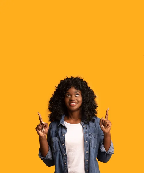 Interested pretty african woman pointing up at copy space — Stock Photo, Image