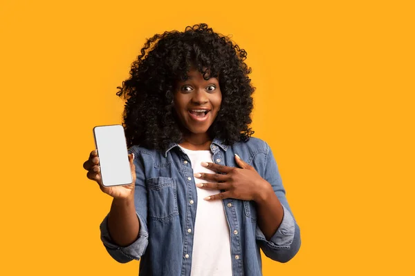 Amazed black lady showing smartphone with empty screen — Stock Photo, Image
