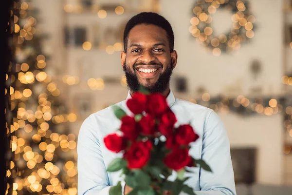 Smiling black man holding roses, giving to camera — Stock Photo, Image
