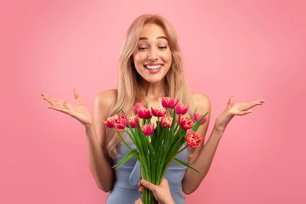 Splendida giovane signora sensazione entusiasta di ricevere mazzo di tulipani per il Womans Day su sfondo rosa studio — Foto Stock