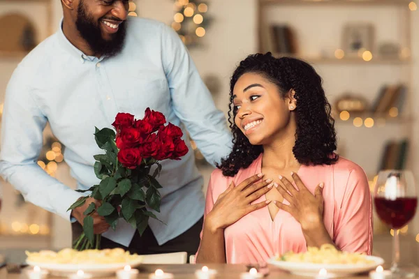 Jeune homme noir donnant des roses rouges à une femme excitée — Photo