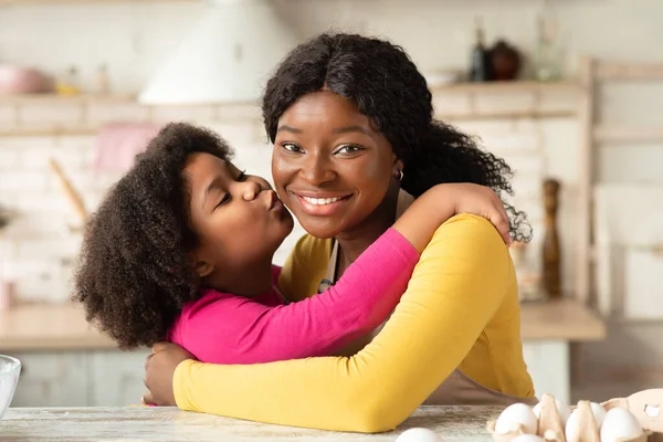 Szczęśliwego Dnia Matki. Little Black Girl całowanie jej szczęśliwy mama w kuchni — Zdjęcie stockowe