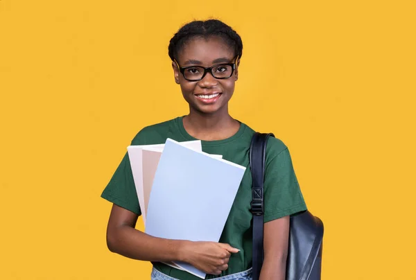 Felice studentessa nera in posa con libri su sfondo giallo — Foto Stock