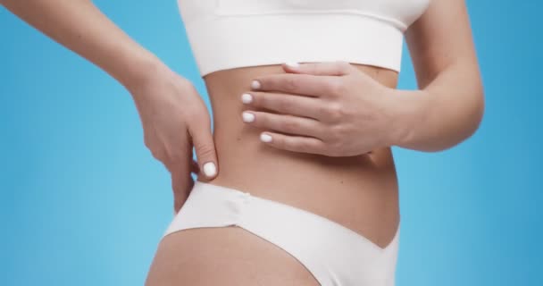 Gros plan de la femme touchant son dos, sentant une inflammation des reins, fond bleu studio — Video