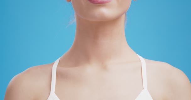 Close-up tiro do pescoço feminino com vermelho pulsante ponto inflamado, dor de garganta doença, fundo estúdio azul — Vídeo de Stock
