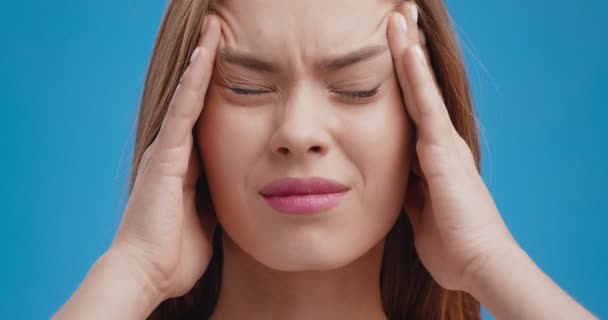 Närbild porträtt av ung kvinna som lider av migrän attack, massera hennes tempel, blodtrycksproblem — Stockvideo