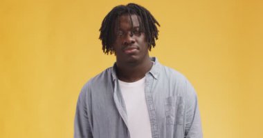 Genç, şüpheci Afro-Amerikan adam. Rasta saçlarıyla gözlerini yuvarlıyor ve kafasını sallıyor. Turuncu arka planda.