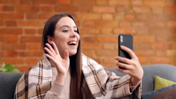 Close up portrait of young cheerful woman video chatting with friends, waving hand hello and talking at home — Stock Video