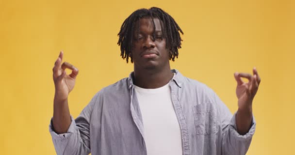 Jong Afrikaans amerikaans hipster guy met dreadlocks mediteren met gesloten ogen, gebaren mudra, oranje achtergrond — Stockvideo