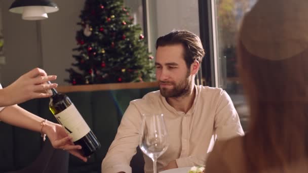 Kellner bringt Flasche Wein, Mann liest und genehmigt sie, lächelt seiner Freundin bei romantischem Date im Restaurant zu — Stockvideo