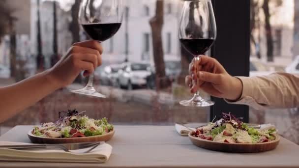 Zbliżenie ujęcia zakochanej pary brzęczące kieliszki do wina podczas romantycznej randki w kawiarni, zwolnione tempo — Wideo stockowe