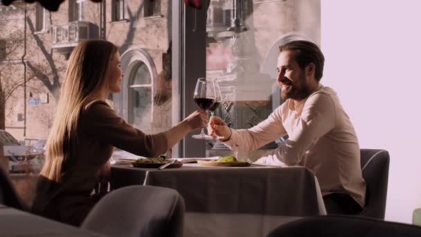 Unga par i kärlek njuter av romantisk dejt i caféet, klänger sig fast med vinglas — Stockvideo